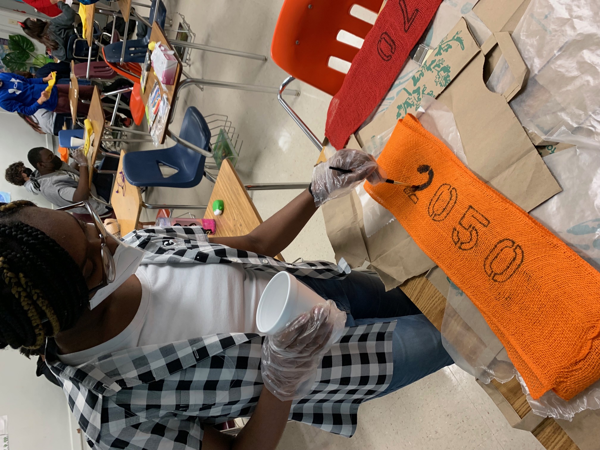 Student painting the year on burlap 